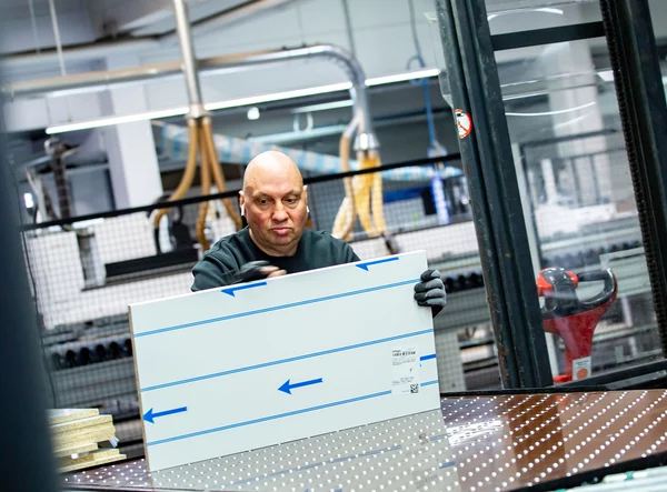 Mitarbeiter hält eine Platte in der Hand und prüft die Maße.