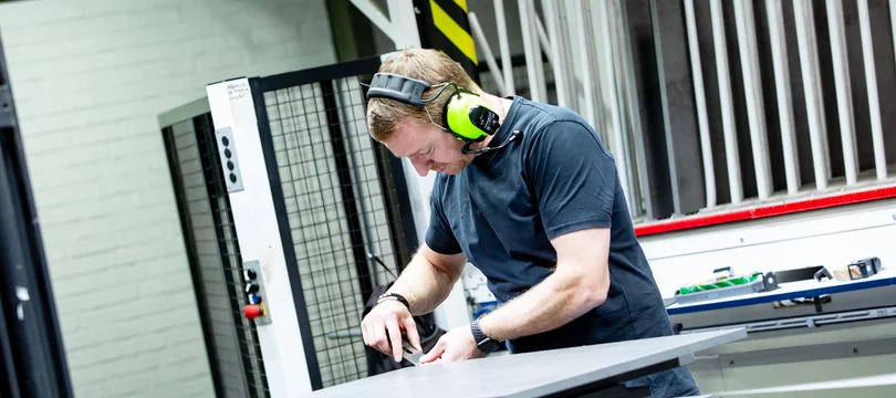 Mitarbeiter von Schiermeier & Niermann montiert ein Scharnier an einer Holzplatte